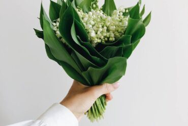 hand holding a bouquet of lily of the valley